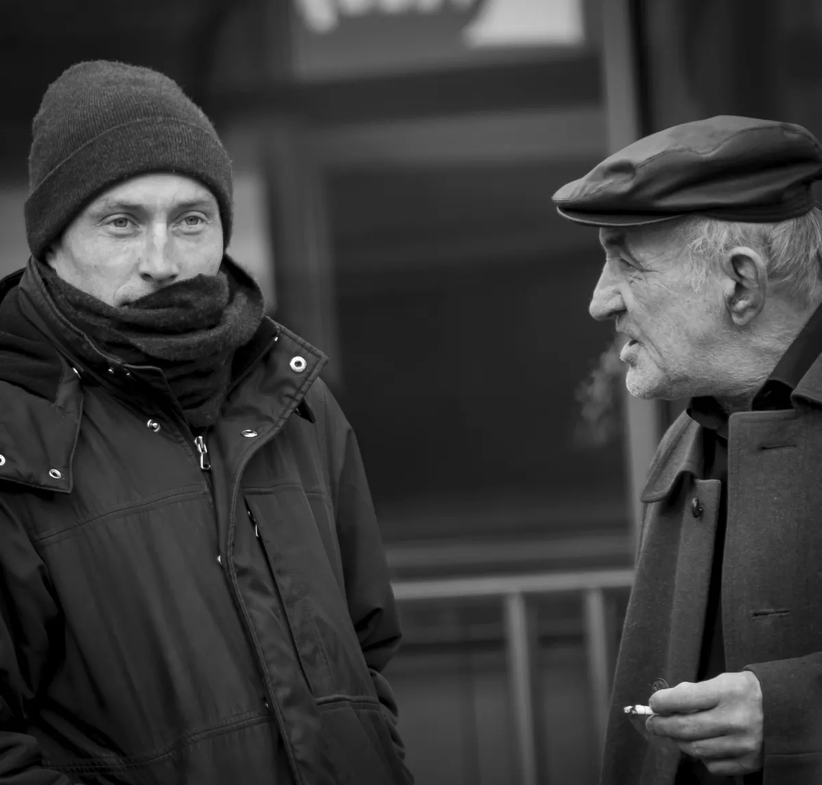 Two men in conversation while one of them smokes